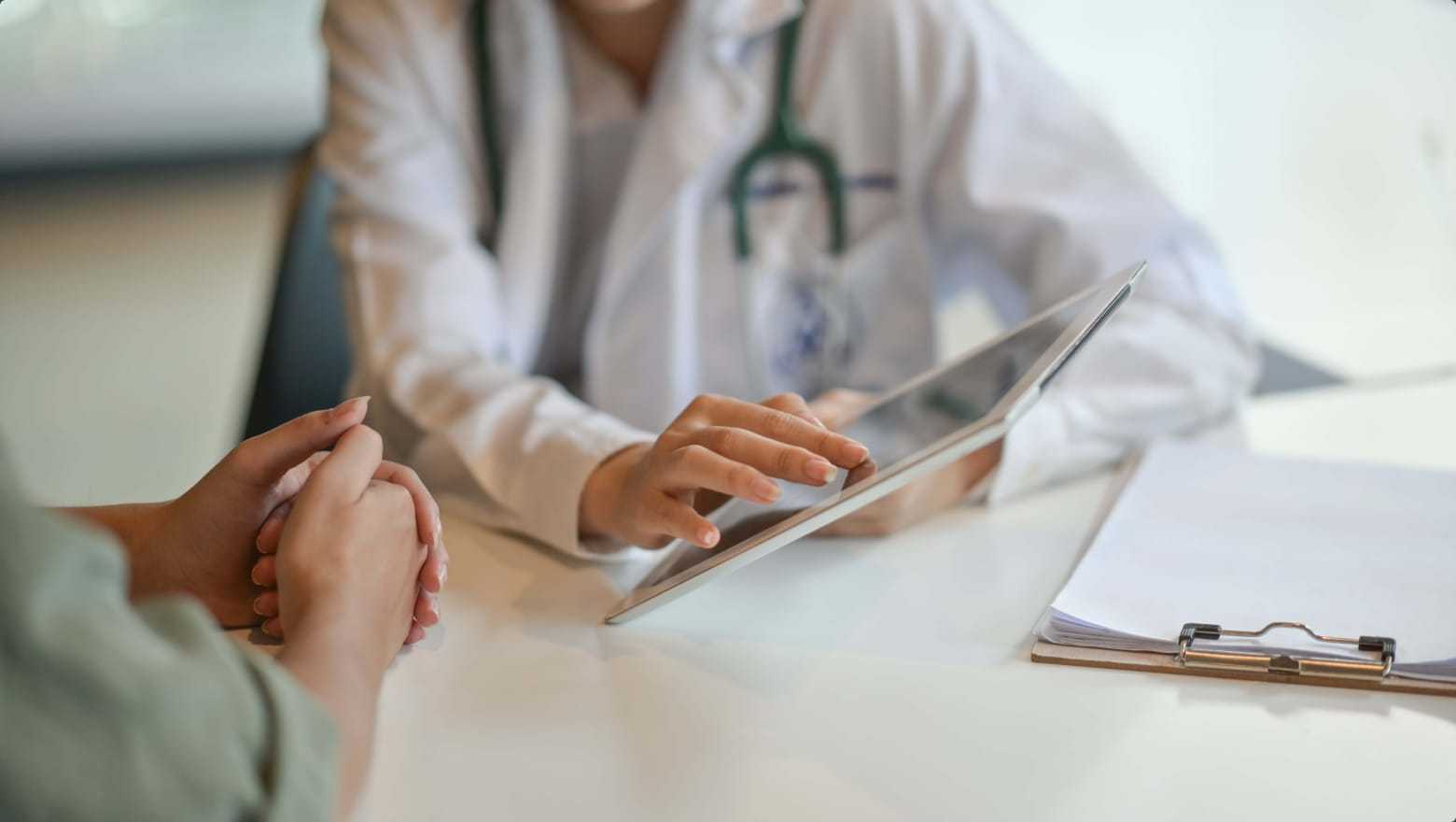 Doctor showing a patient information on tablet computer.