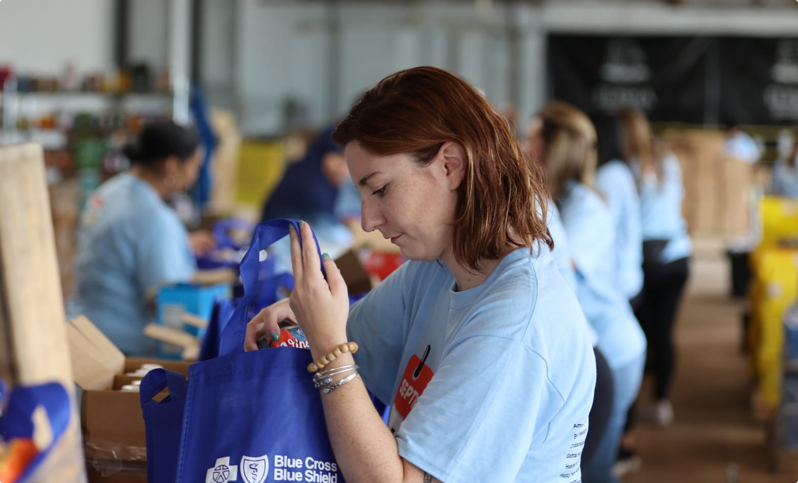 A BCBSRI volunteer packing food into a Blue Cross Blue Shield of RI branded reusable bag.